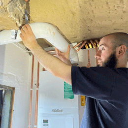 Engineer fitting pipework to a boiler